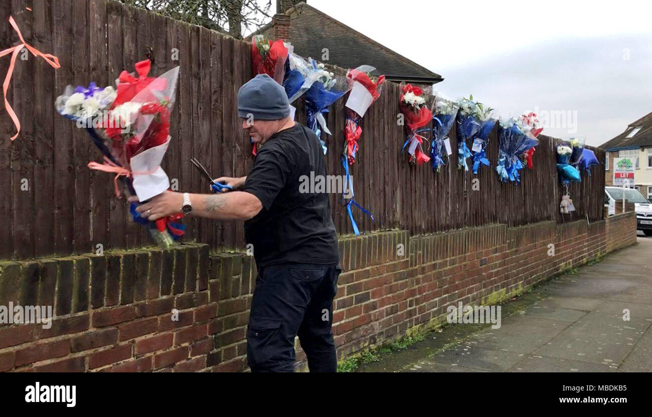 Un homme supprime les tributs floraux d'une clôture sur South Park Crescent dans Hither Green, minutes après des proches de 37 ans, Henry Vincent restauré le culte en face de la maison de Richard, Osborn-Brooks 78, où Vincent a été poignardé à la suite d'un cambriolage raté. Banque D'Images