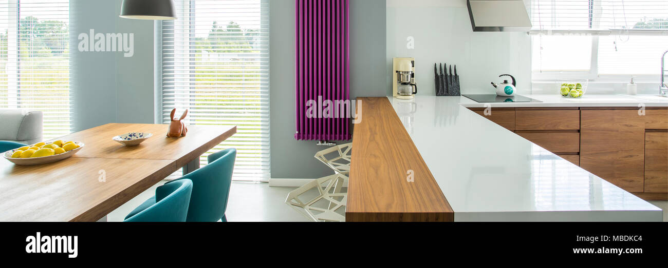 Comptoir blanc et violet à l'intérieur de chauffage cuisine moderne avec table à manger en bois Banque D'Images