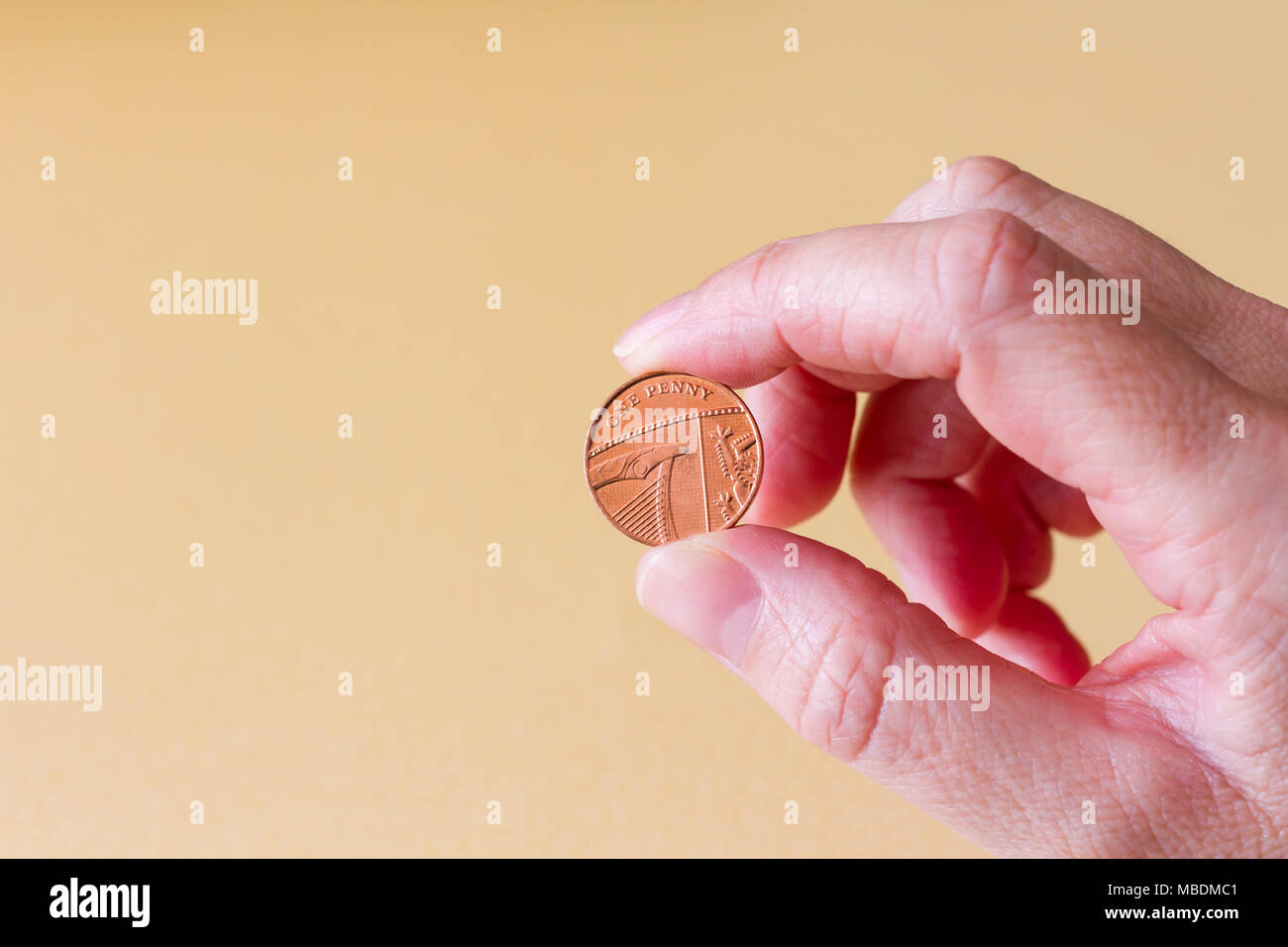 Une main de femme tenant un penny, un pence sterling britannique coin Banque D'Images
