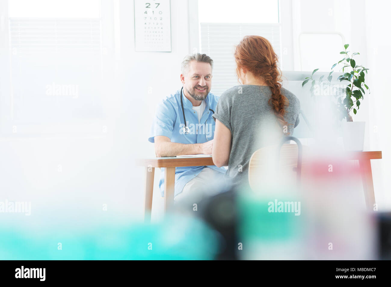 Beau médecin portant un uniforme de parler à une femme dans le bureau Banque D'Images