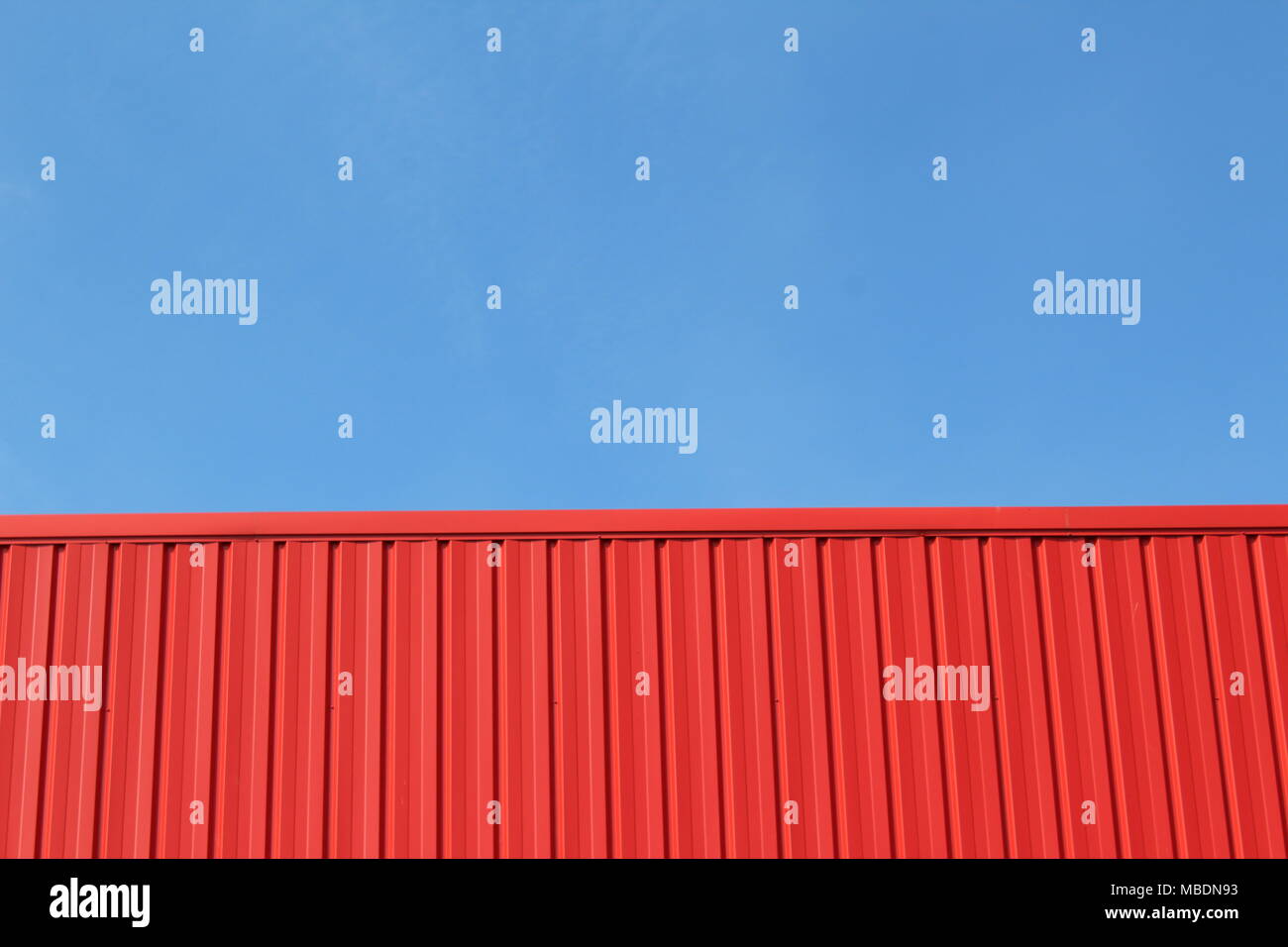 Paysage urbain minimaliste avec un bâtiment rouge et un ciel bleu clair Banque D'Images