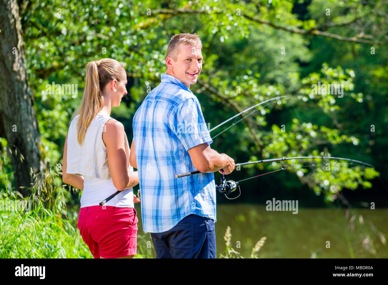 Pêche La pêche à la ligne ou jeune couple debout sur la rive de la rivière Banque D'Images