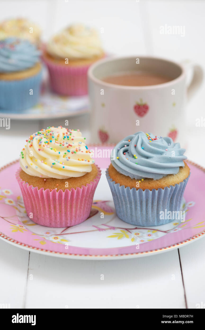 Cupcakes vanille colorés sur une plaque avec une tasse de thé Banque D'Images