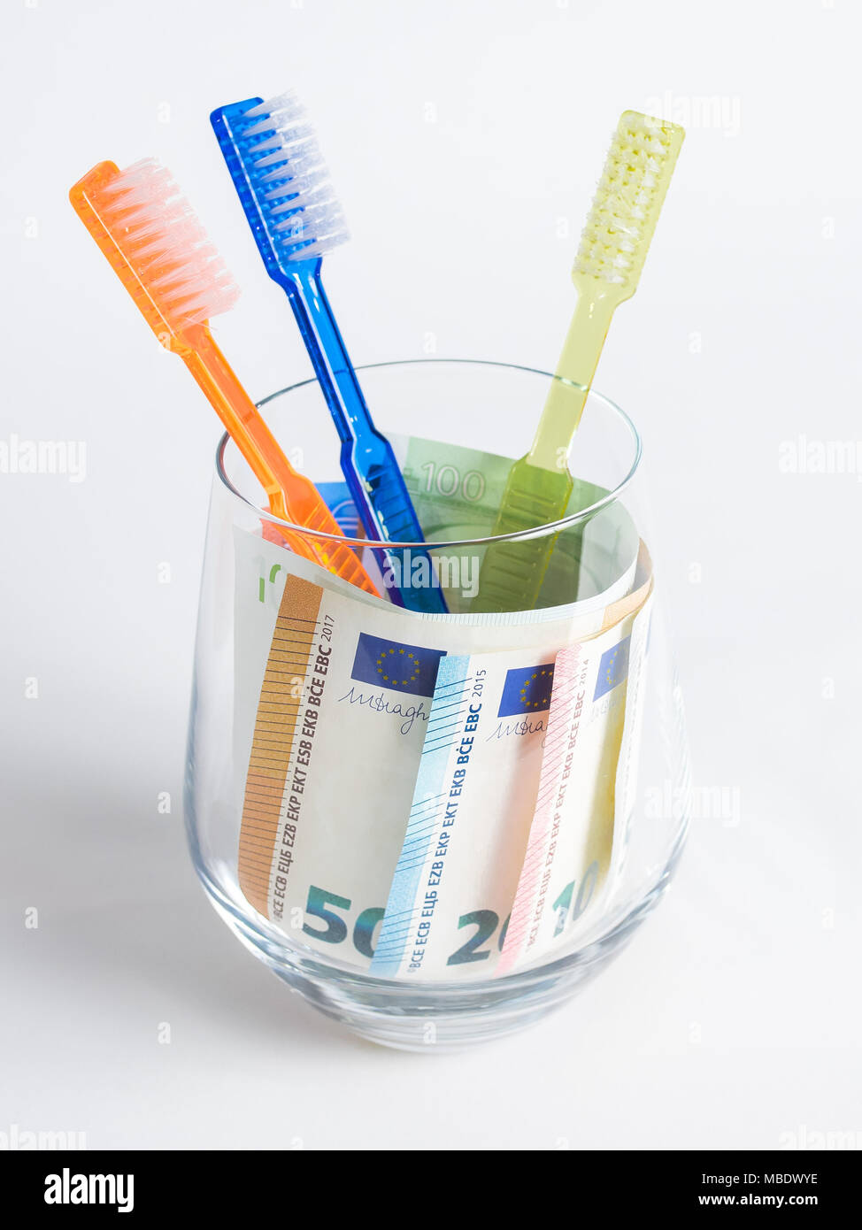 Des brosses à dents en verre avec de l'argent en euros dans le verre Banque D'Images