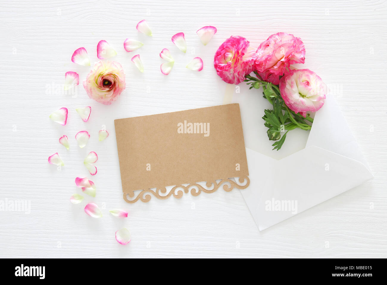 Image de l'enveloppe avec de belles fleurs rose pastel délicates sur fond de bois blanc arrangement. Mise à plat, vue du dessus Banque D'Images