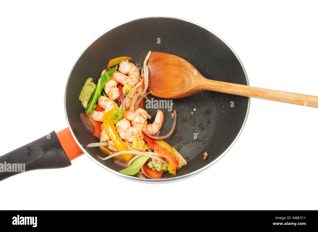 Langoustines et faire sauter les légumes avec une cuillère en bois dans un wok isolés contre white Banque D'Images