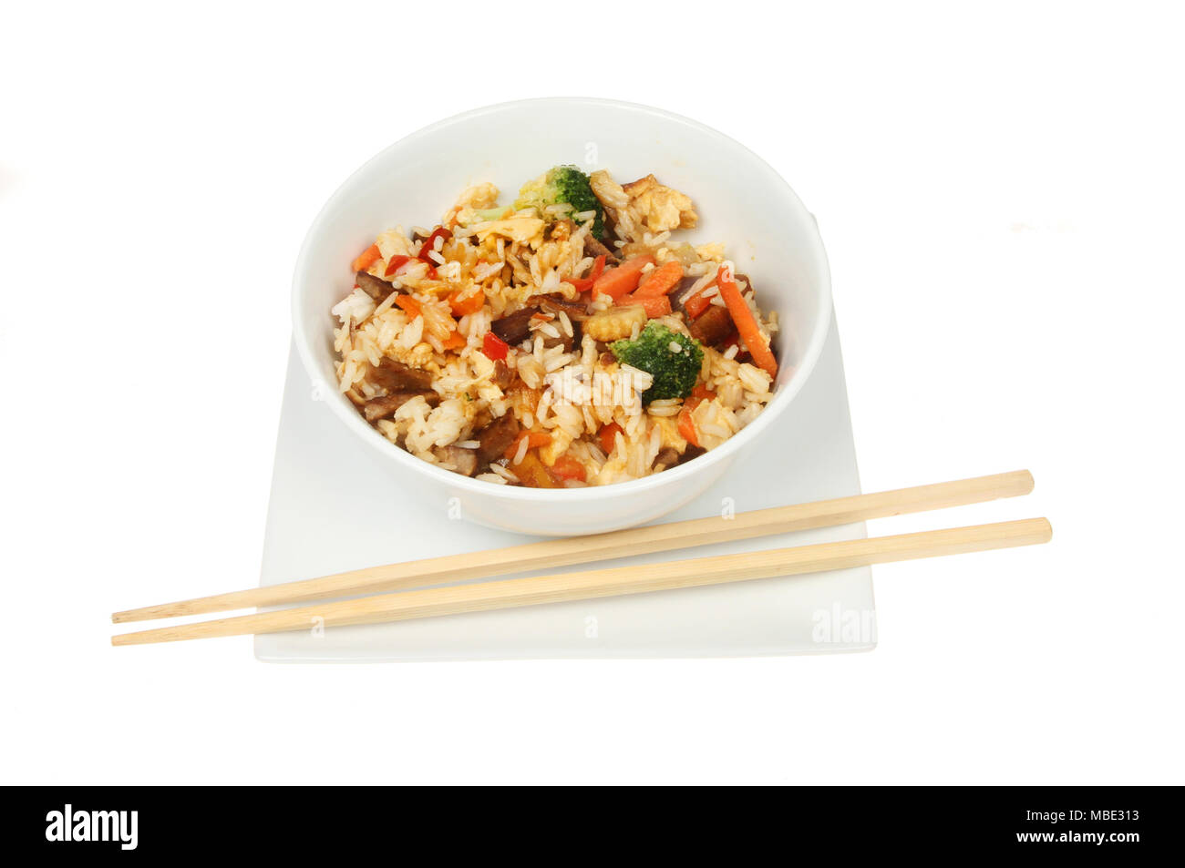 Riz frit au porc et légumes dans un bol avec des baguettes sur une plaque isolés contre white Banque D'Images