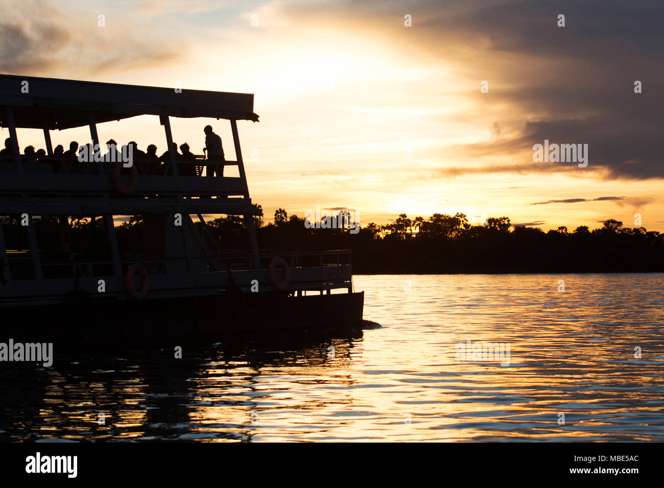 Un bateau au cours d'une croisière au coucher du soleil sur le fleuve Zambèze, près de Victoria Falls au Zimbabwe. Les croisières au coucher du soleil offrent un moyen de l'observation de la faune et des oiseaux. Banque D'Images