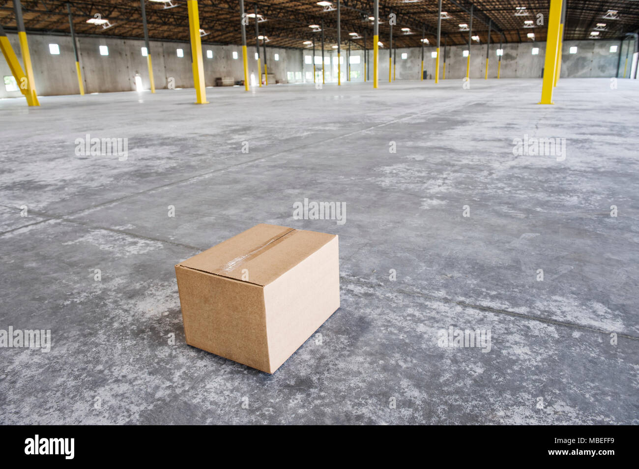 Boîte en carton unique au milieu d'un nouvel entrepôt vide de l'espace. Banque D'Images