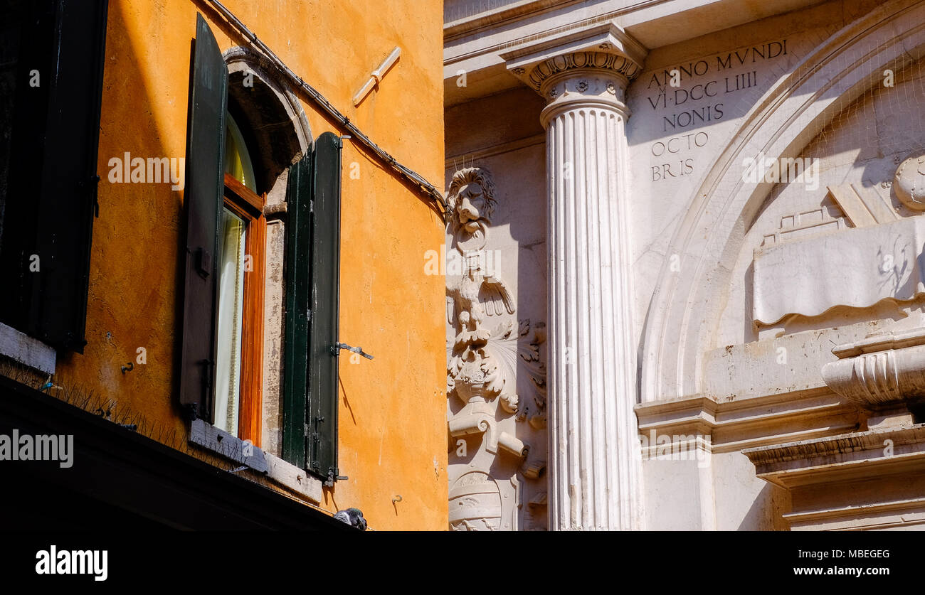 Le côté d'une maison aux volets et fenêtre et ornate church avec colonne en pierre Banque D'Images