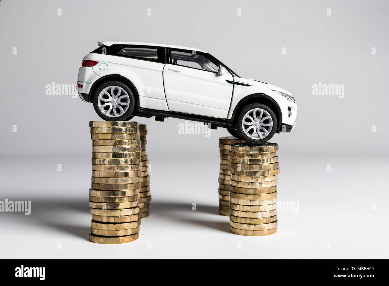 Un jouet Land Rover Evoque en équilibre sur des piles de £1 pièces. Banque D'Images