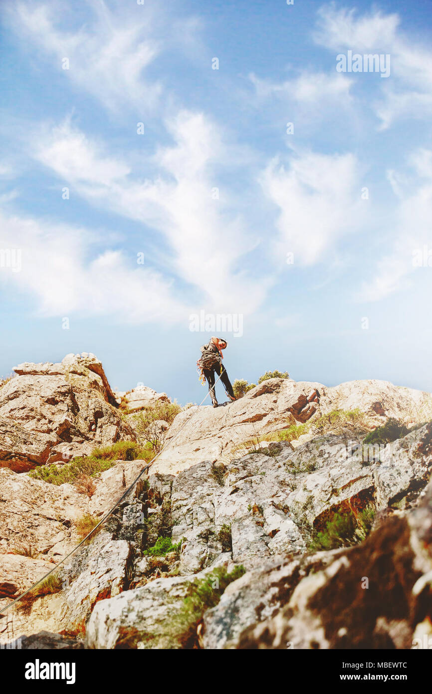 Rock climber atteindre haut de rochers Banque D'Images