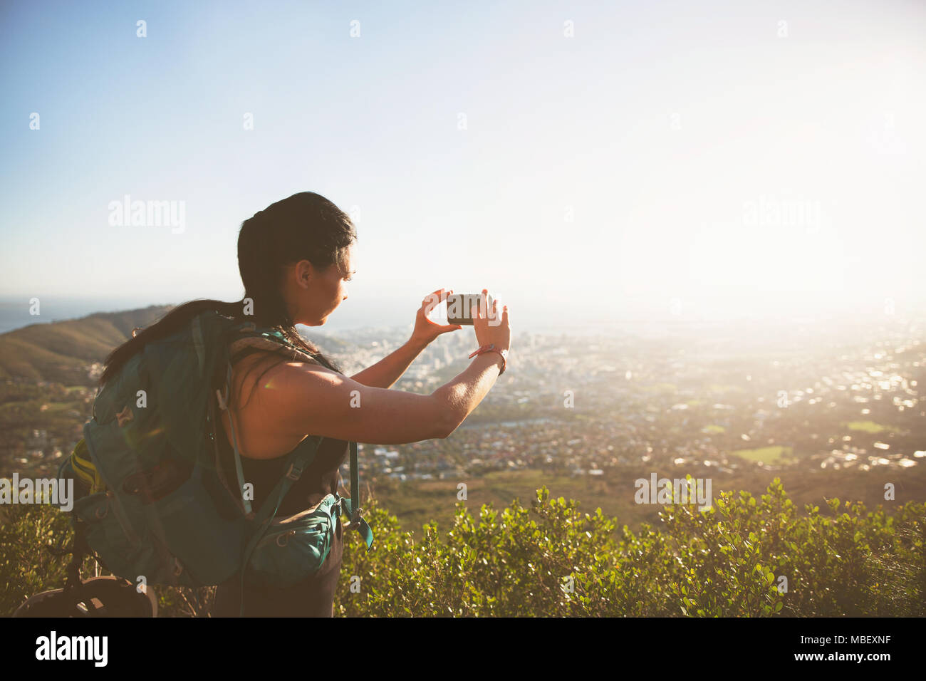 Backpacker femelle avec téléphone appareil photo photographier sunny vue sur la ville Banque D'Images