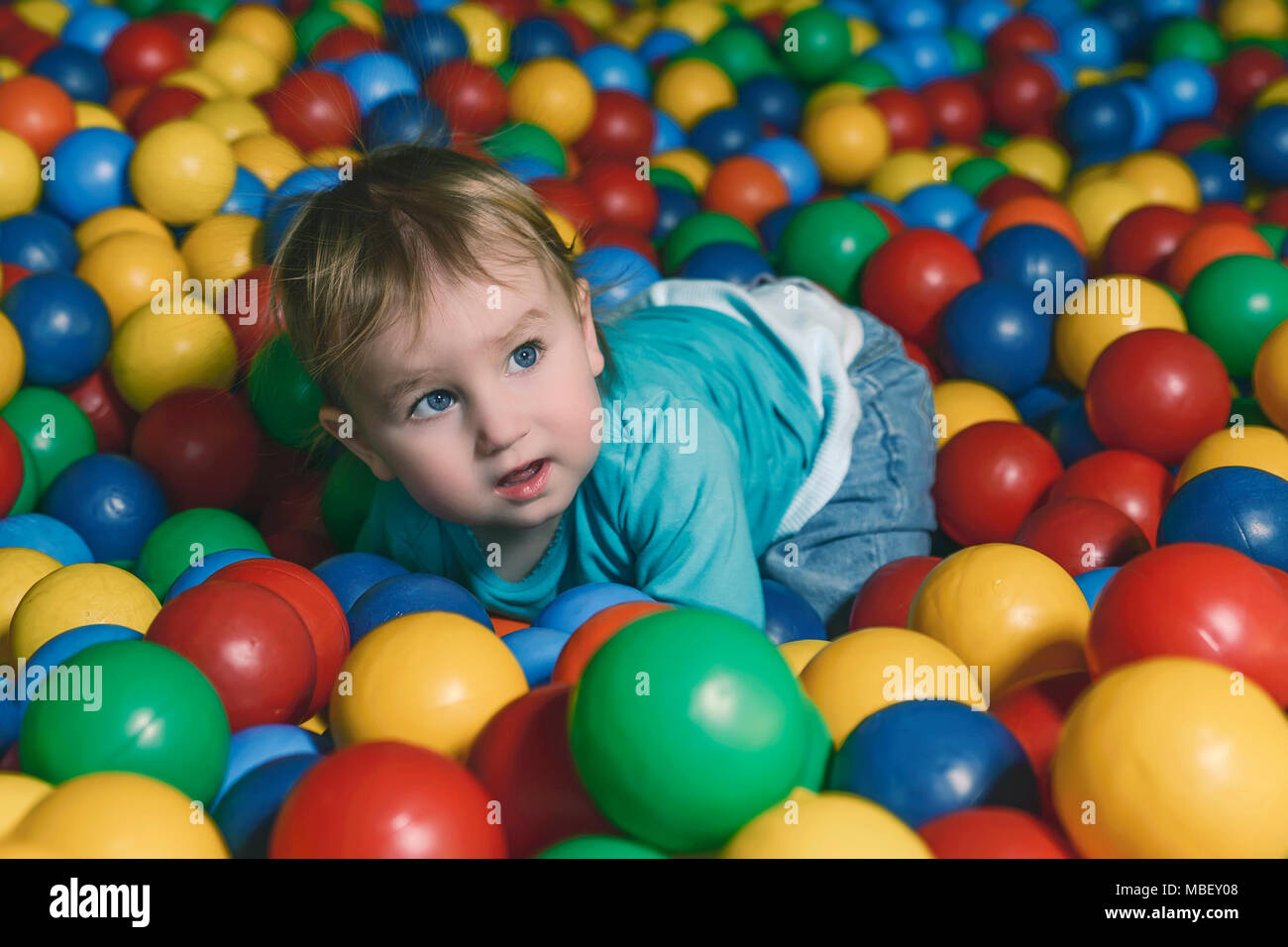 Heureux petit enfant joue sur une aire remplie de billes en plastique coloré Banque D'Images