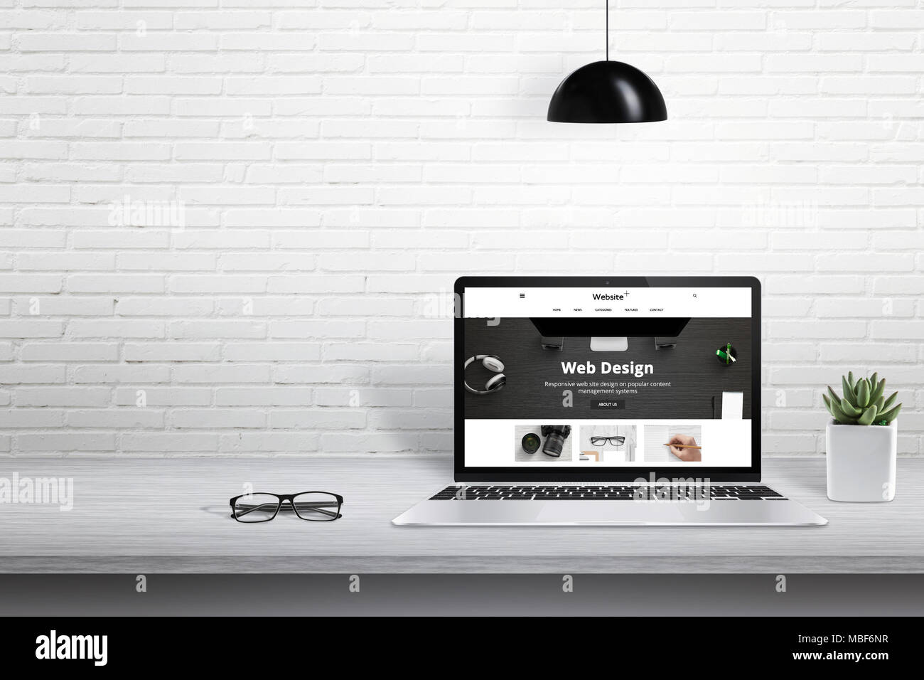 Ordinateur portable avec le site web moderne exposé. Espace libre pour le texte à côté sur mur de briques blanches. Banque D'Images