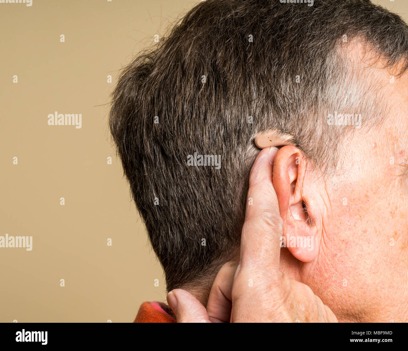 Hauts homme portant une petite aide auditive moderne caché derrière l'oreille Banque D'Images