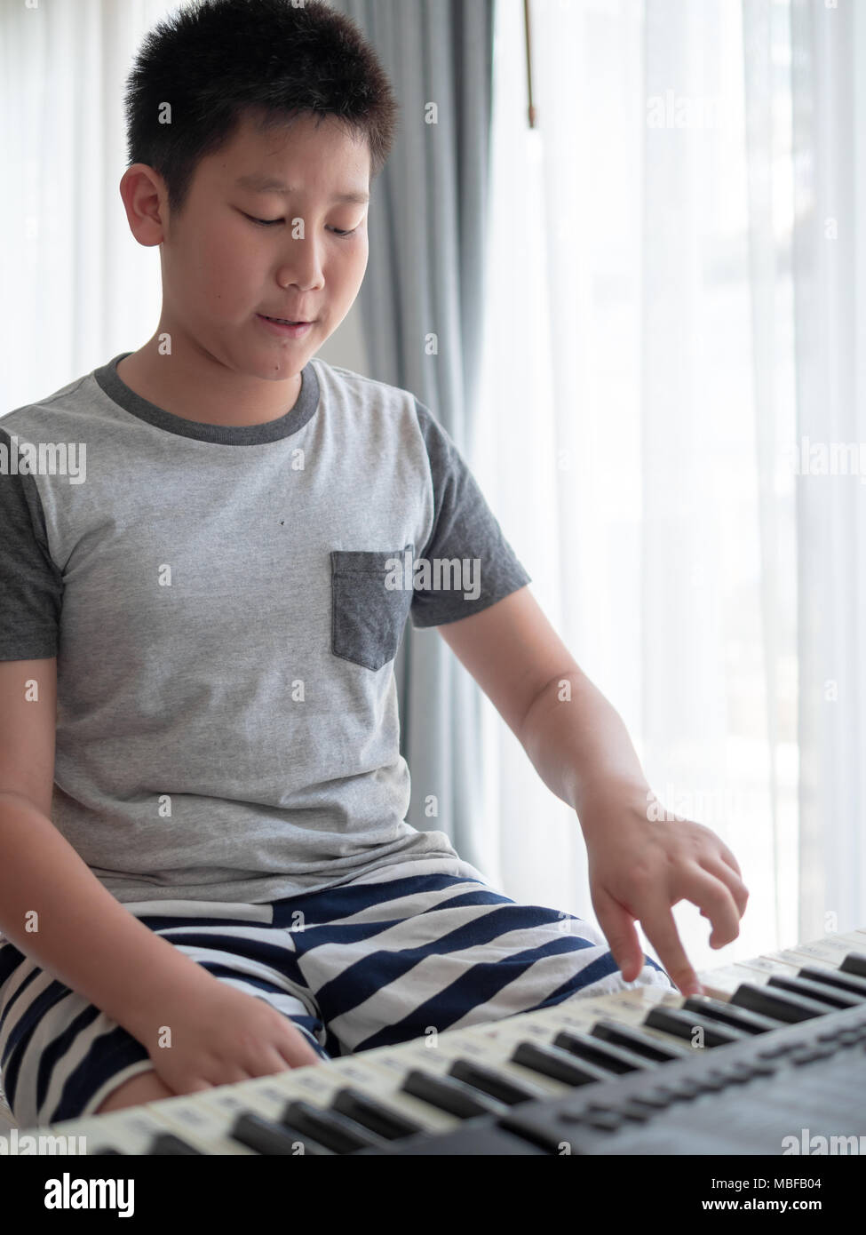 asiatique garçon en jouant le synthétiseur ou piano. mignonne peu enfant  apprentissage Comment à jouer piano. enfant mains sur le clavier intérieur.  33504751 Photo de stock chez Vecteezy