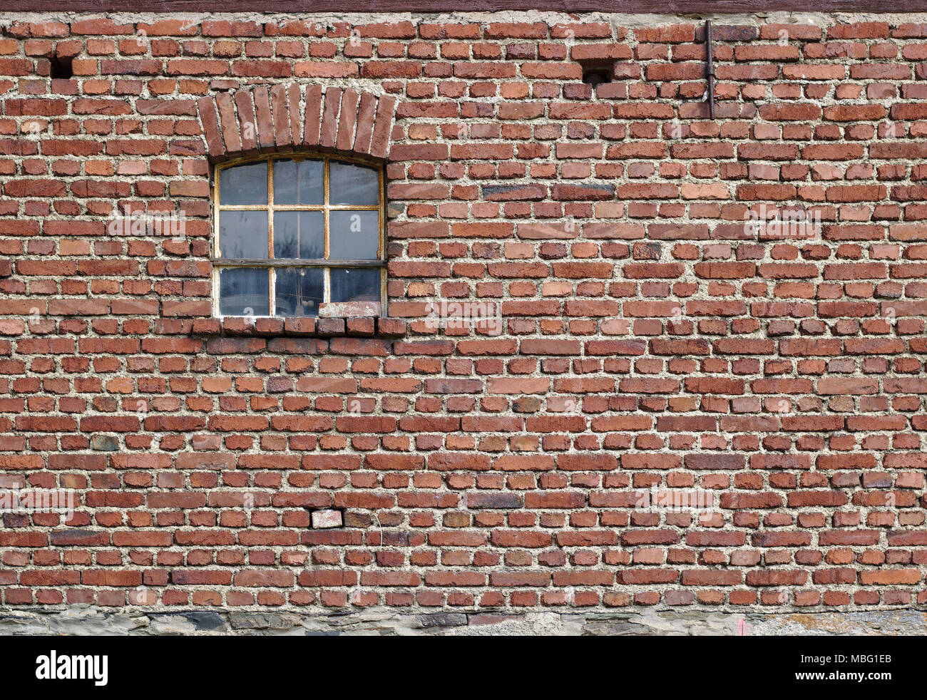 Vintage mur de brique rouge avec fenêtre rouillée et fondations en pierre sur le terrain Banque D'Images