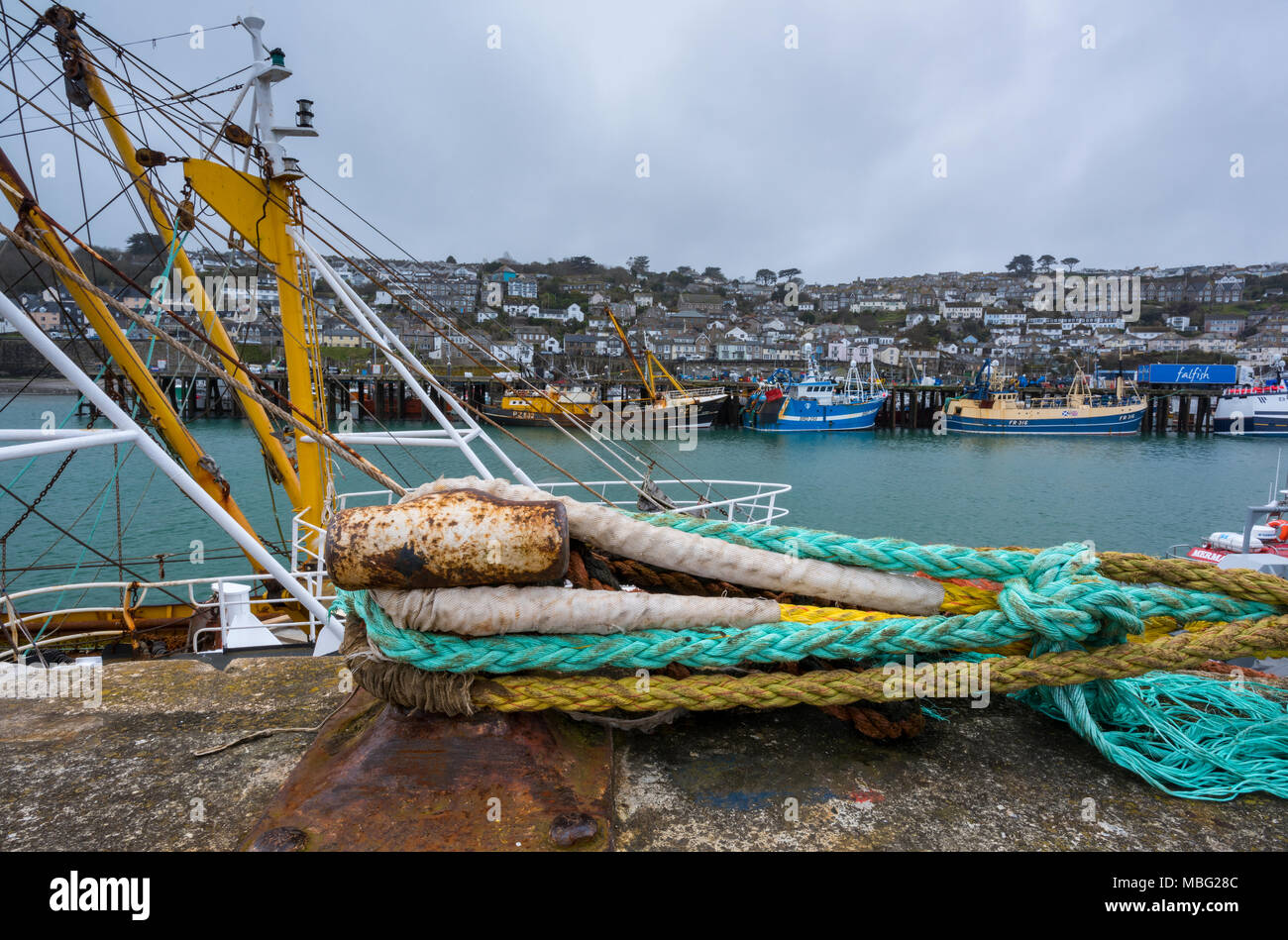 Des cordes attachées à un point fixe sur le mur du port de Newlyn à Cornwall. Les bateaux de pêche amarrés à quai et le long du mur dans un Cornish principal port de pêche. Banque D'Images