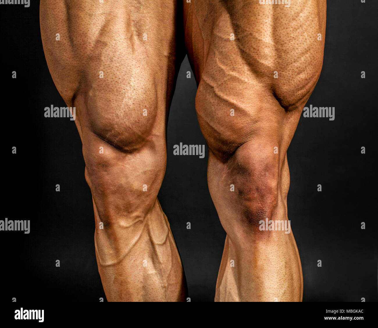 Détail de male bodybuilder muscles de jambe avant sur fond noir. Quadriceps et le muscle tibial antérieur. Banque D'Images