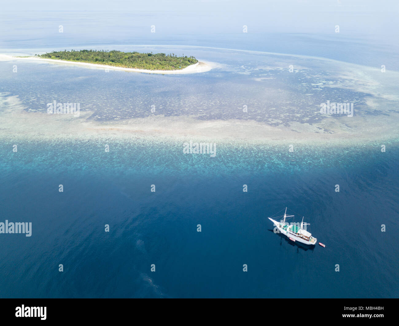 Un Pinisi goélette dérive près d'une île tropicale, à distance dans la mer de Banda. Cette région est dans le Triangle de Corail et a une grande biodiversité marine. Banque D'Images