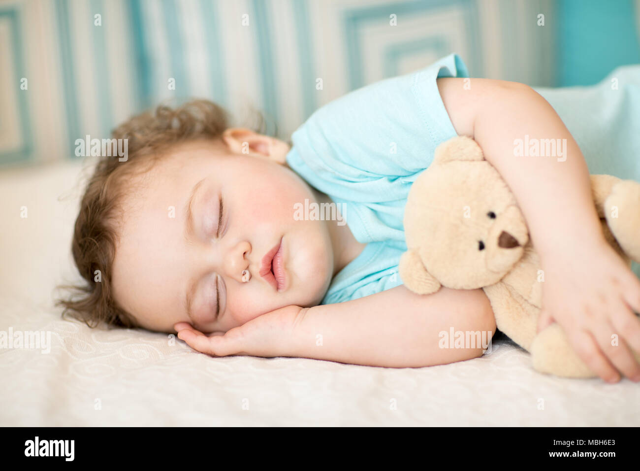 Bébé sommeil insouciant avec soft toy on bed Banque D'Images