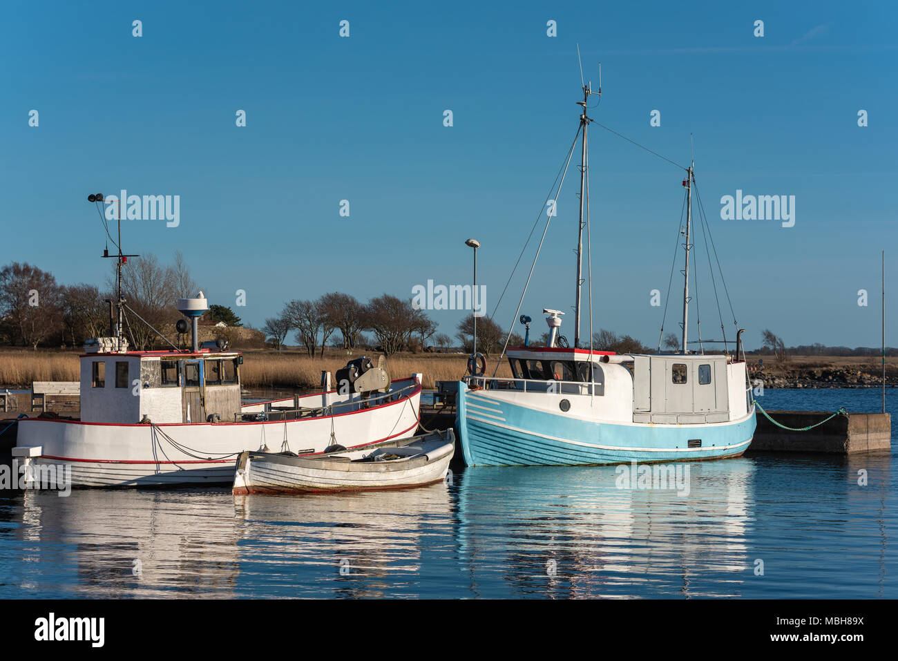 Anciens et bien utilisé les bateaux de pêche amarrés au port sur un soir de printemps dans Gronhogen sur Oland, Sweden. Les noms et logos déposés. Banque D'Images