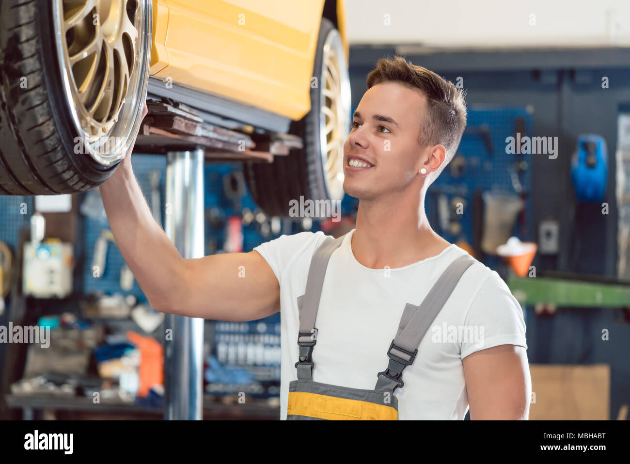 Portrait of a smiling spécialiste tuning pendant le contrôle de roues de voiture à l'écoute Banque D'Images