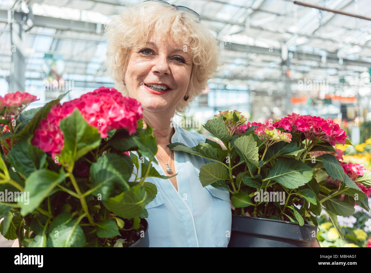 Portrait d'une active senior woman holding potted plantes ornementales Banque D'Images