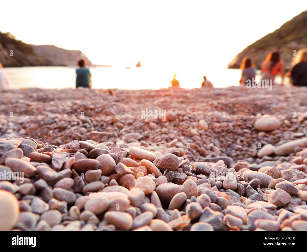 Les gens à regarder le coucher du soleil sur la plage de Benirras, Ibiza. Coucher de soleil idyllique scène à la mer avec l'accent sur l'avant-plan et l'espace de copie. Banque D'Images