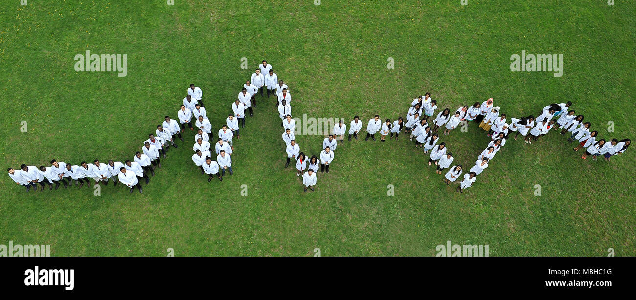 Kiev, Ukraine - 22 Avril 2018 : les étudiants en médecine debout sur l'herbe, faire vivre coeur graphique. Les personnes de nationalités différentes. Physycians vêtus de blanc uniforme médical. L'action de bienfaisance. Banque D'Images