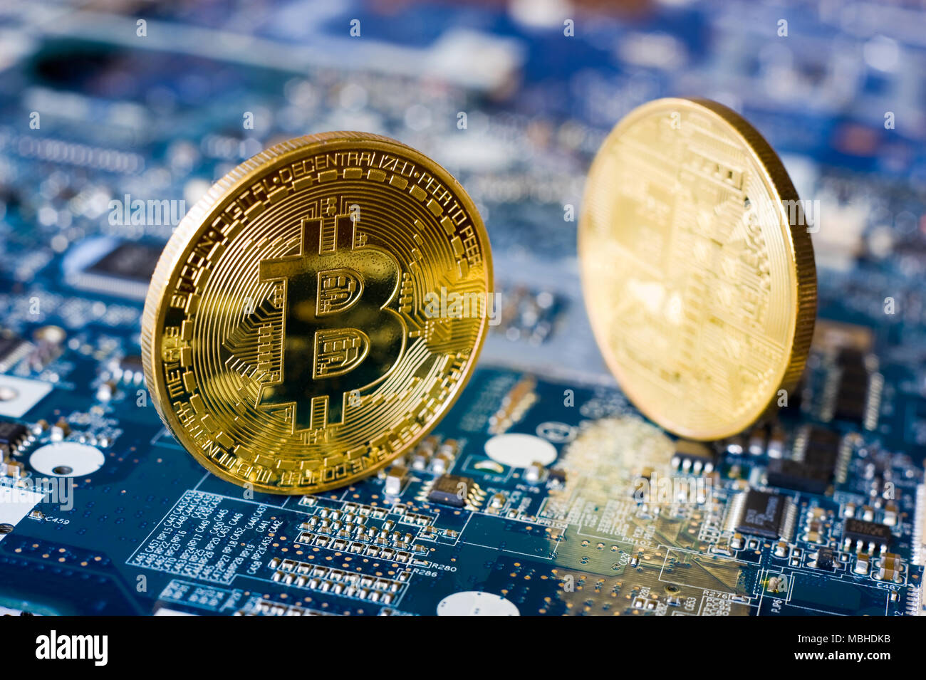 Deux des bitcoins debout sur la carte mère électronique d'un ordinateur portable Banque D'Images