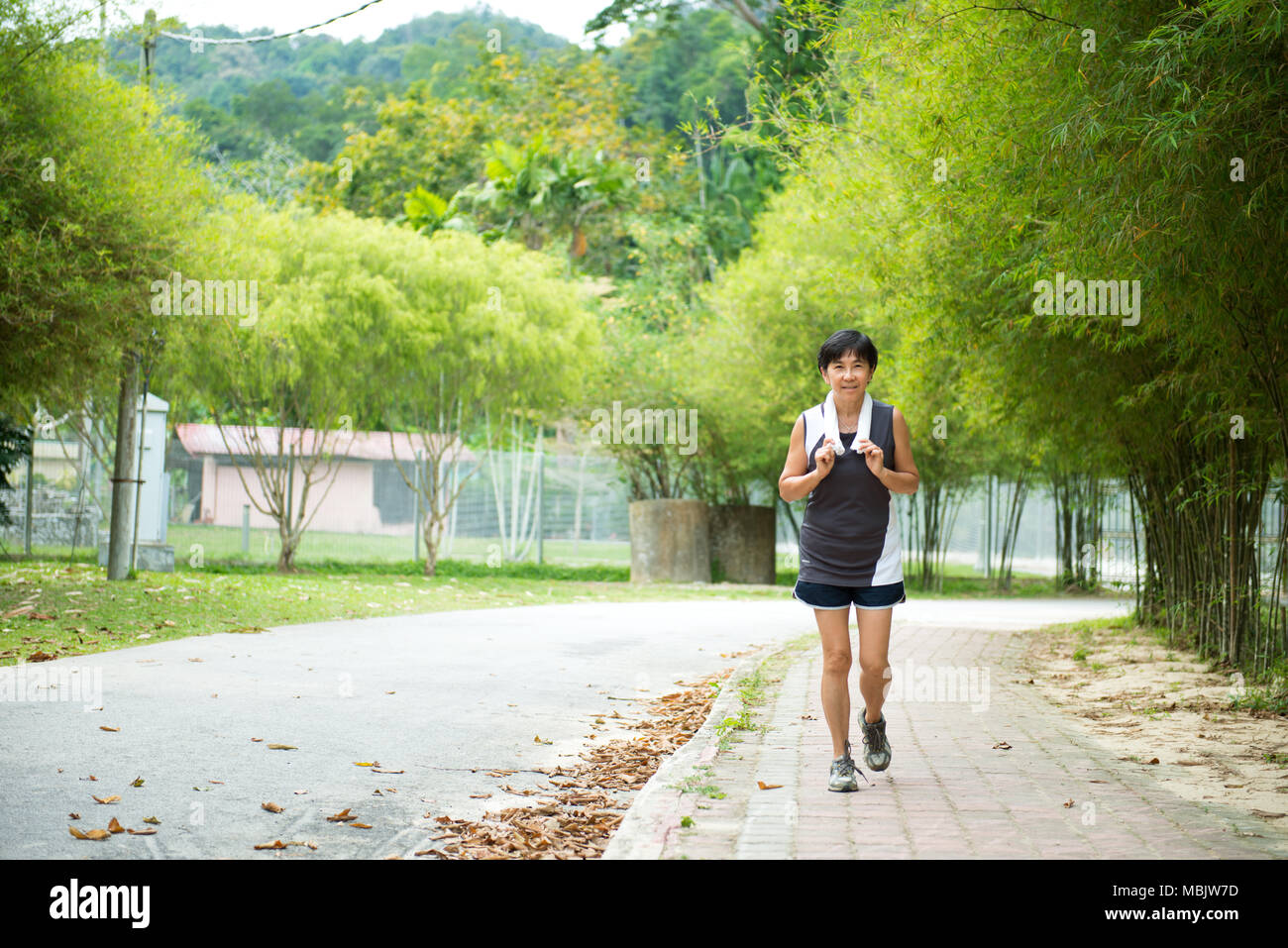 Vue avant du senior woman jogging through park Banque D'Images