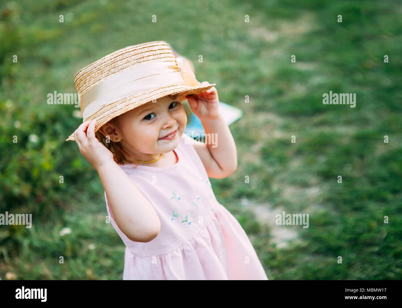 Cute baby girl portrait.petite fille dans un chapeau de paille sourit et regarde l'espace pour le texte de l'appareil photo Banque D'Images