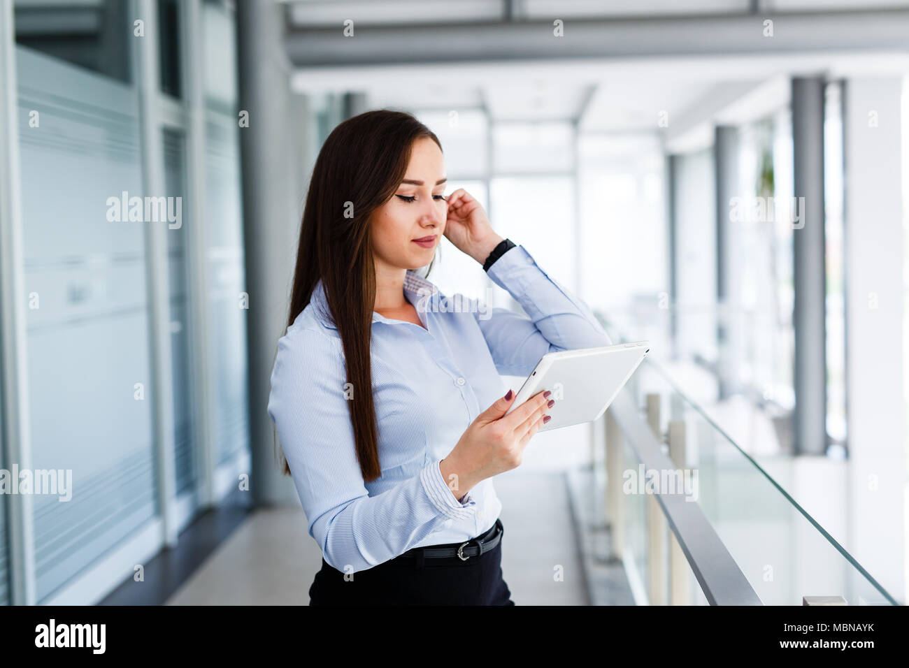 Belle femme de toucher ses cheveux et à la recherche sur tablette Banque D'Images