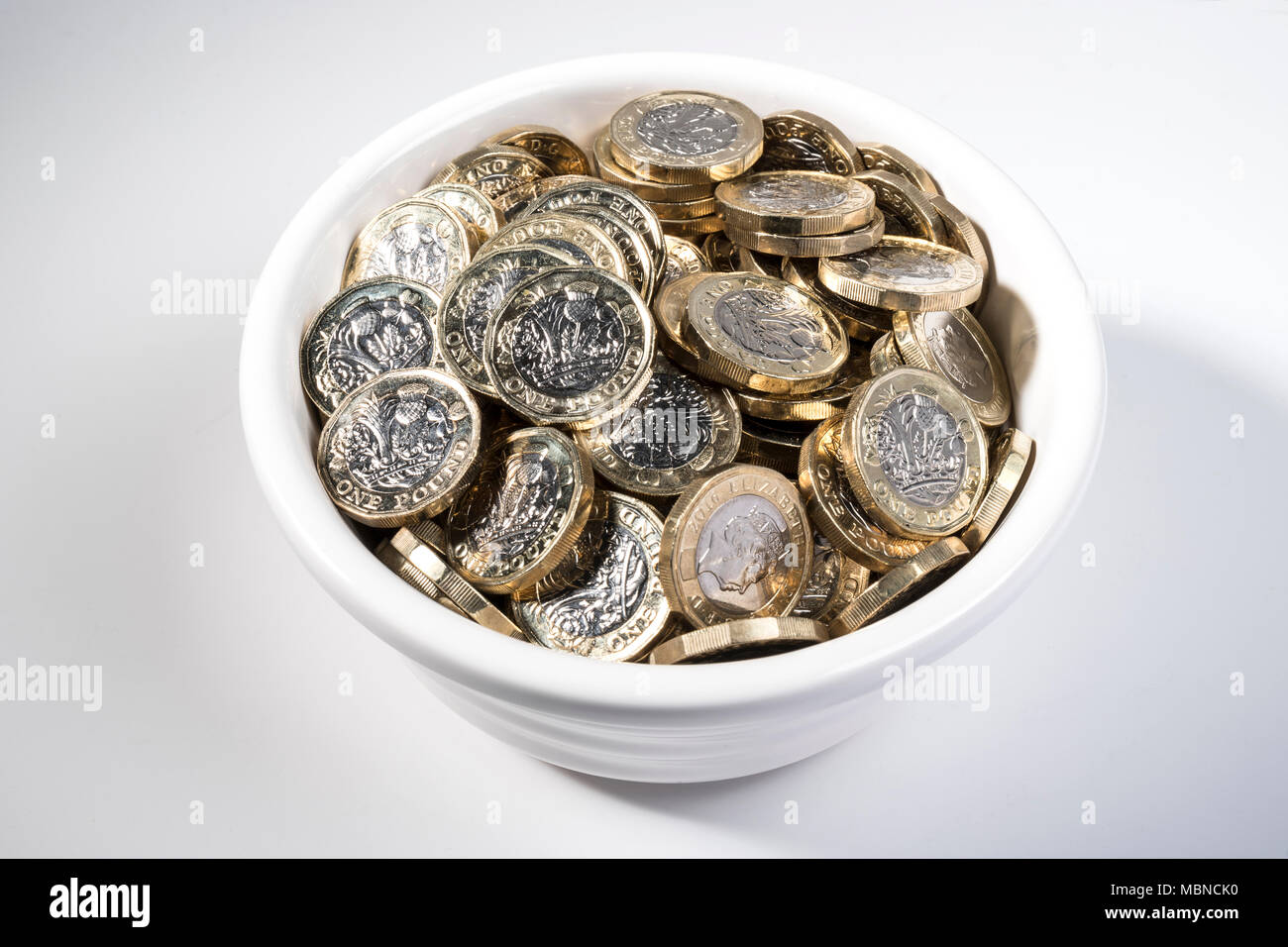 €1 pièces dans un bol en céramique blanche. Banque D'Images