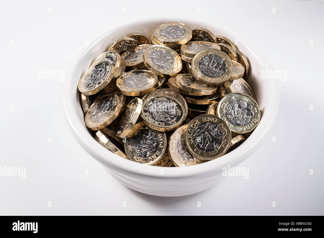 €1 pièces dans un bol en céramique blanche. Banque D'Images