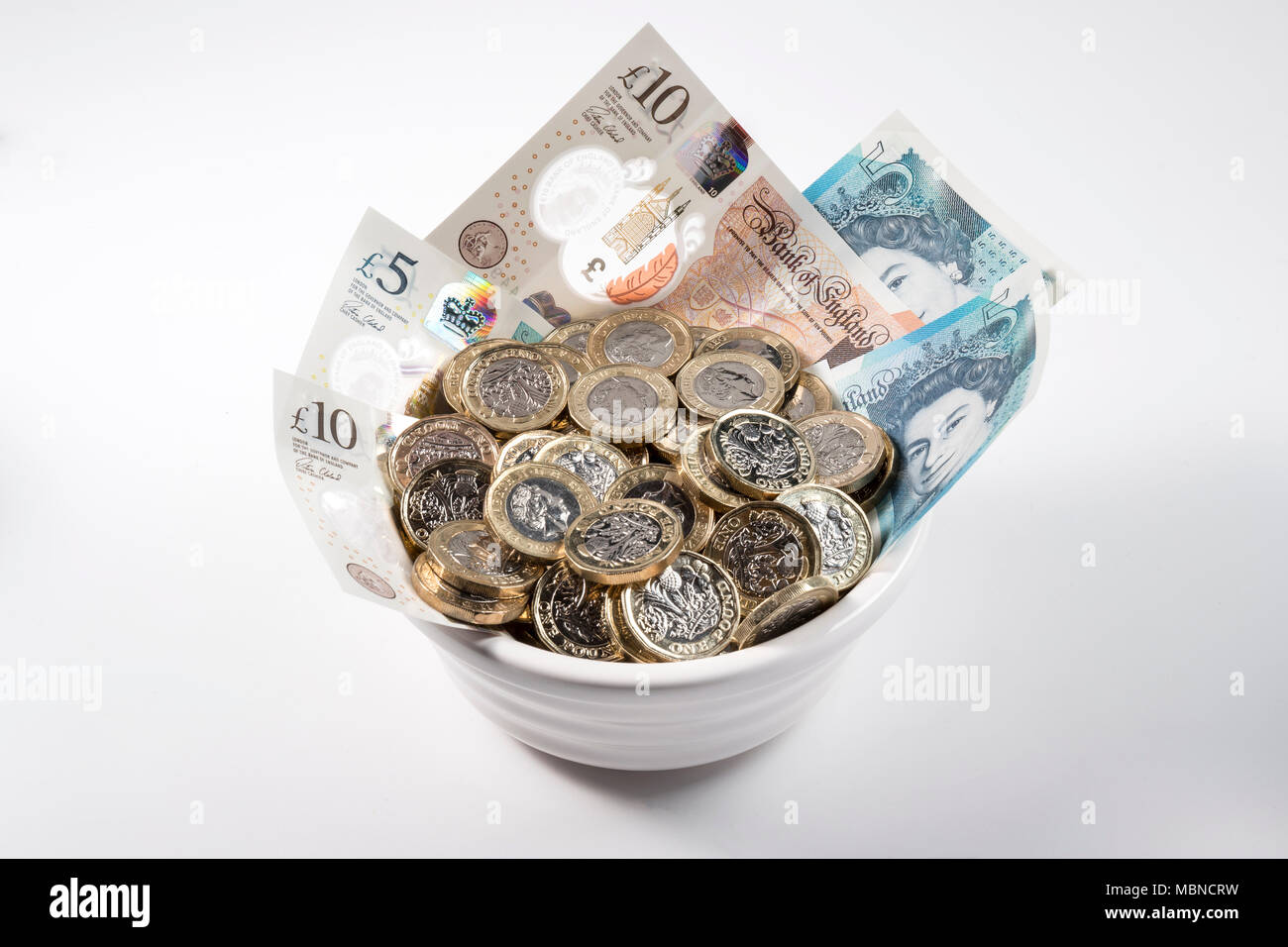 €1 pièces de monnaie et de billets dans un bol en céramique blanche. Banque D'Images