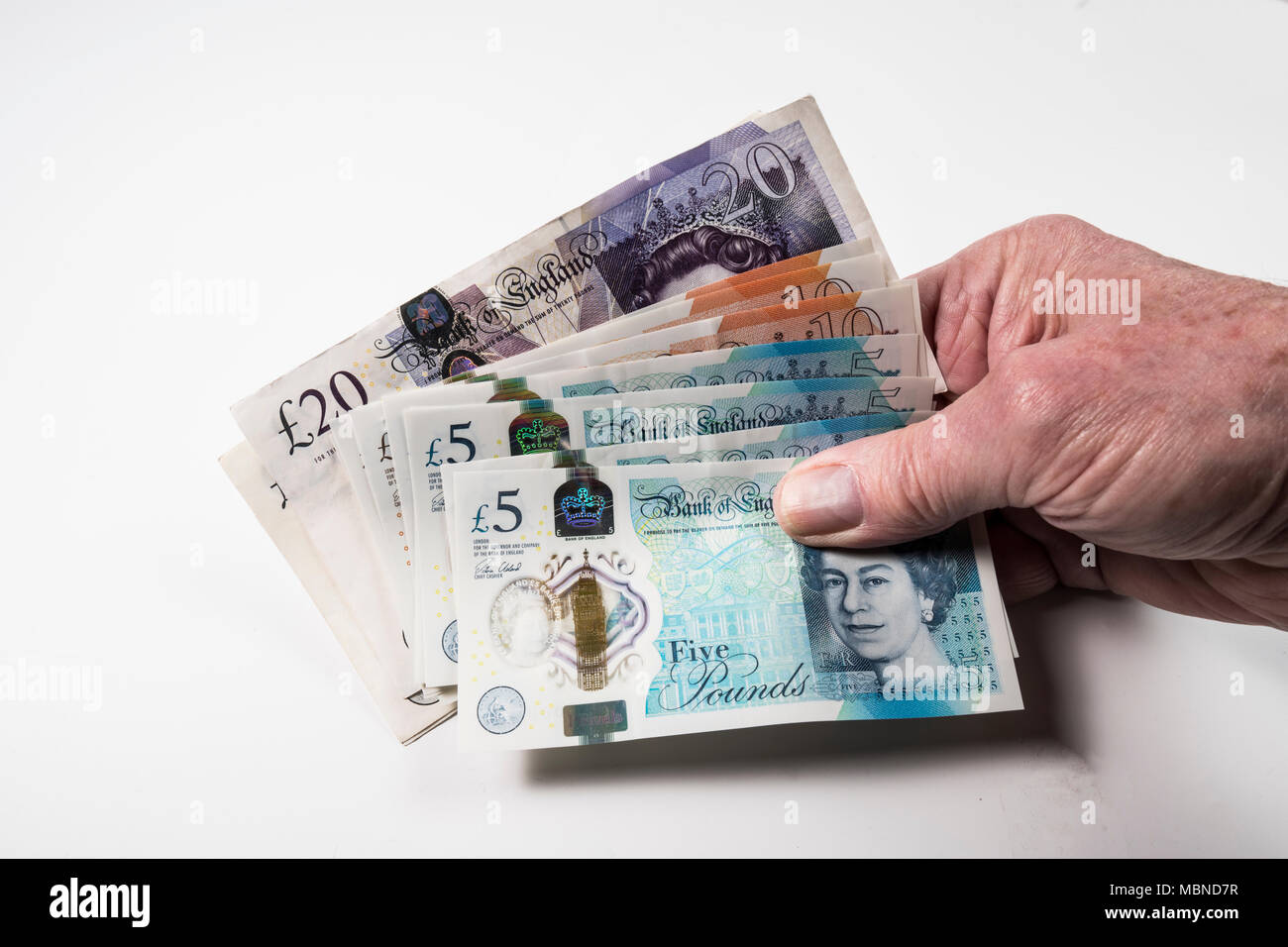 Un mâle hand holding UK argent, £5 pound, £10 et £20 pound pound notes dans un ventilateur Banque D'Images