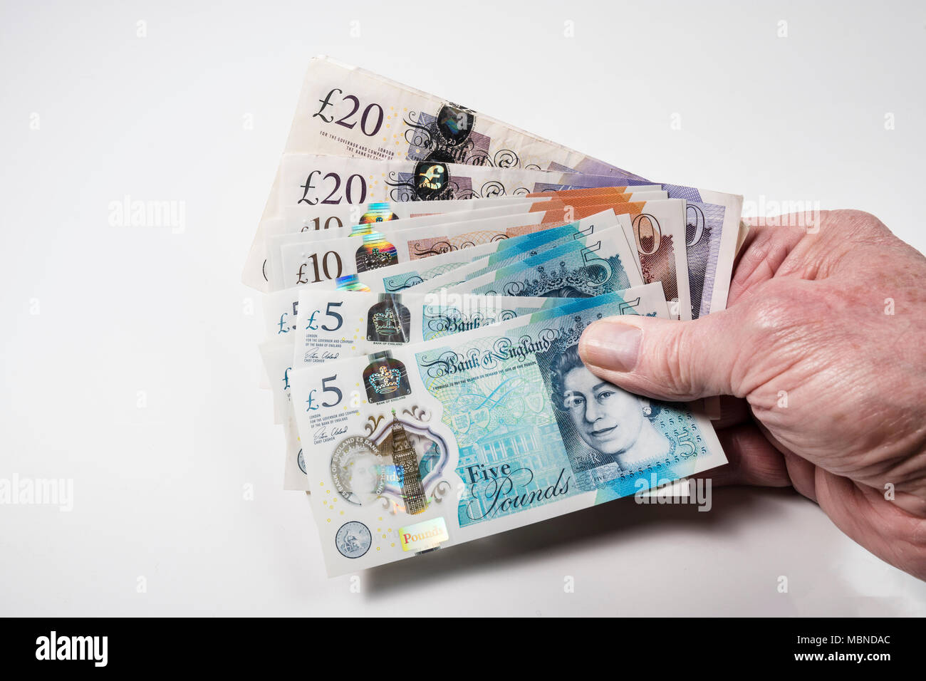 Un mâle hand holding UK argent, £5 pound, £10 et £20 pound pound notes dans un ventilateur Banque D'Images
