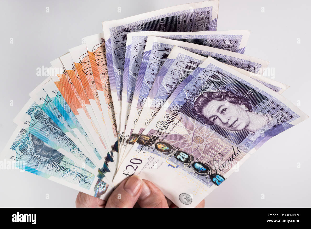 Un mâle hand holding UK argent, £5 pound, £10 et £20 pound pound notes dans un ventilateur Banque D'Images