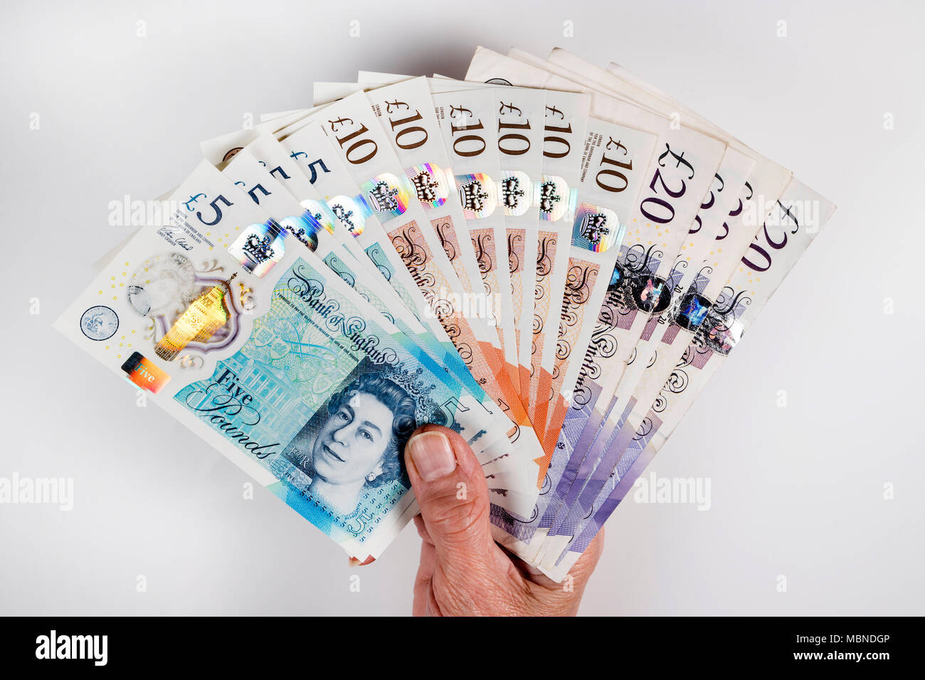 Un mâle hand holding UK argent, £5 pound, £10 et £20 pound pound notes dans un ventilateur Banque D'Images