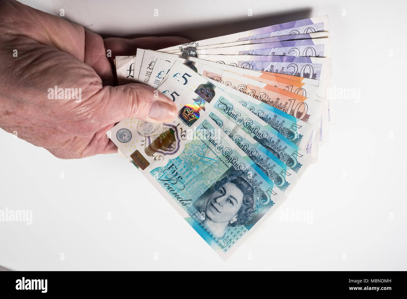 Un mâle hand holding UK argent, £5 pound, £10 et £20 pound pound notes dans un ventilateur Banque D'Images