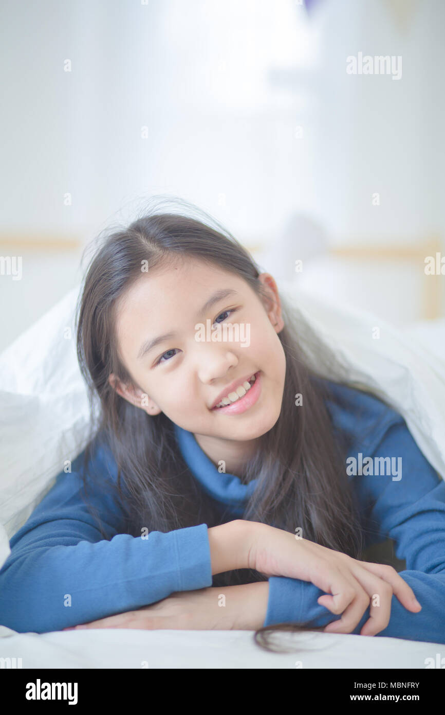 Happy Asian girl lying on the bed avec sun light sur lazy day Banque D'Images