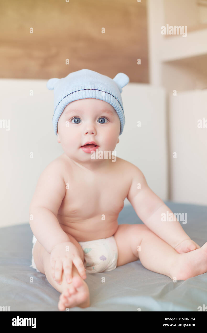 Peu drôle bébé garçon aux grands yeux bleus smiling avec capuchon mignon avec des oreilles sur la tête. Piscine Banque D'Images