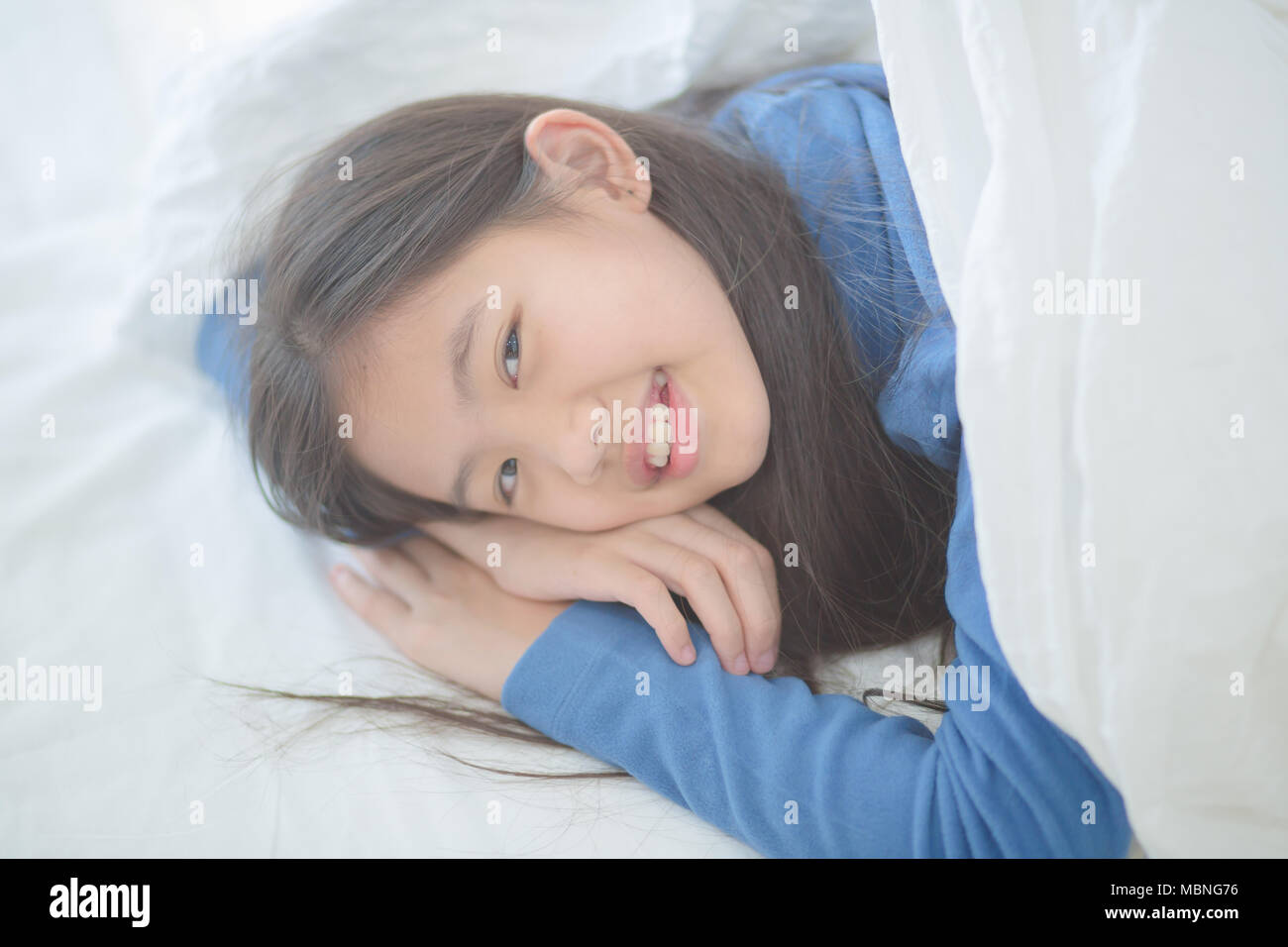 Happy Asian girl lying on the bed avec sun light sur lazy day Banque D'Images