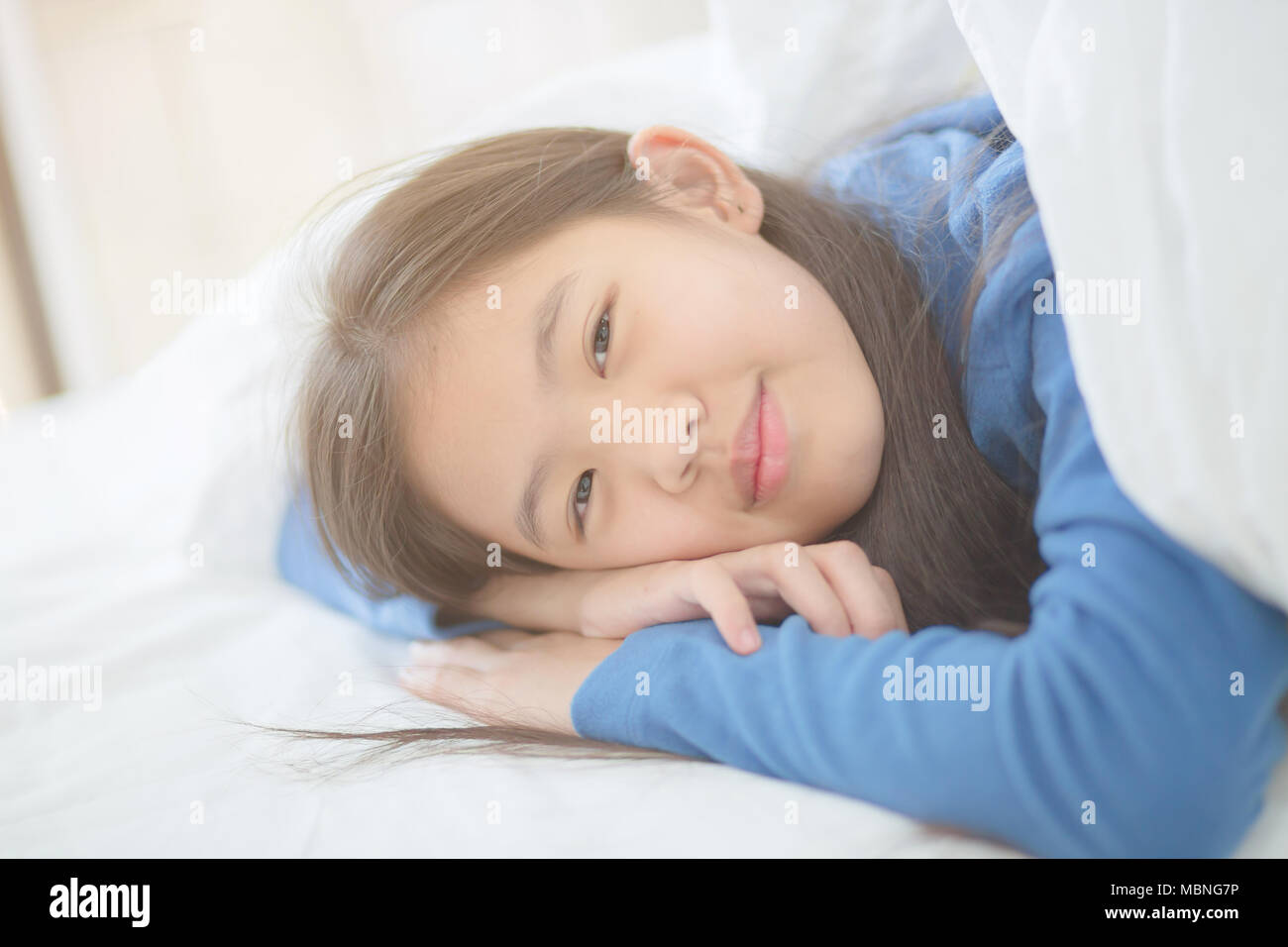 Happy Asian girl lying on the bed avec sun light sur lazy day Banque D'Images