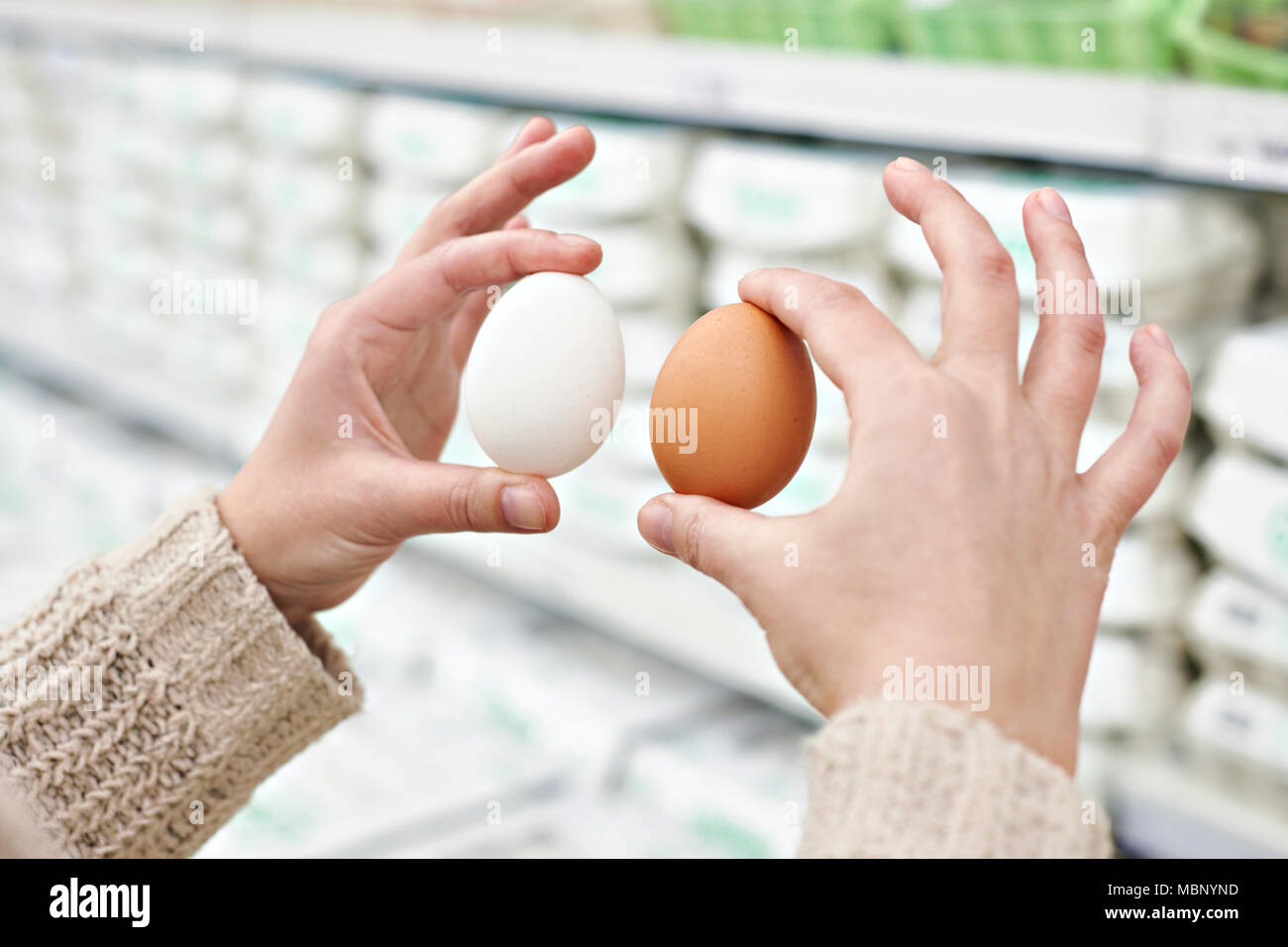 Mains d'une femme avec le blanc et le brun oeufs dans le magasin Banque D'Images