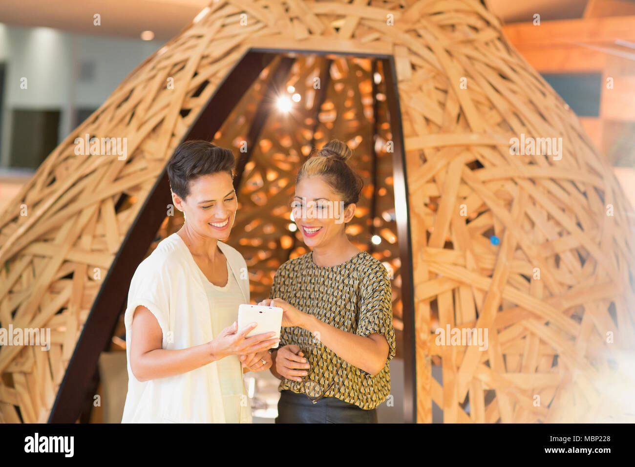 Smiling creative businesswomen using smart phone at espace créatif tipi Banque D'Images