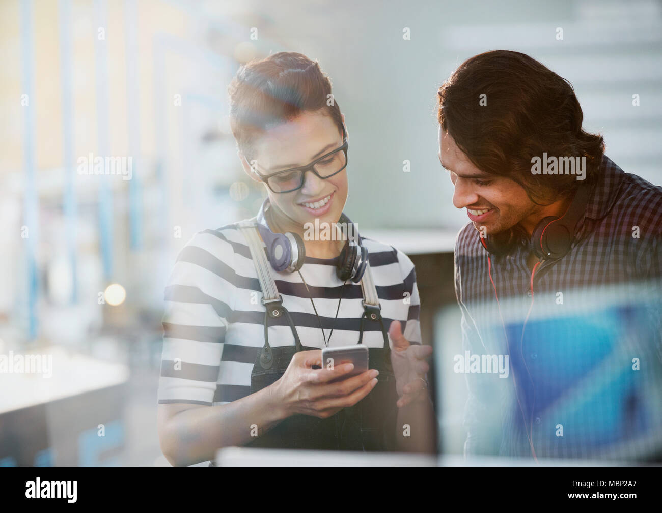 Les gens d'affaires créatifs avec des écouteurs à l'aide de smart phone in office Banque D'Images